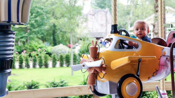 Photo d'un bébé assis dans les petits avions du Carrousel du parc Bagatelle