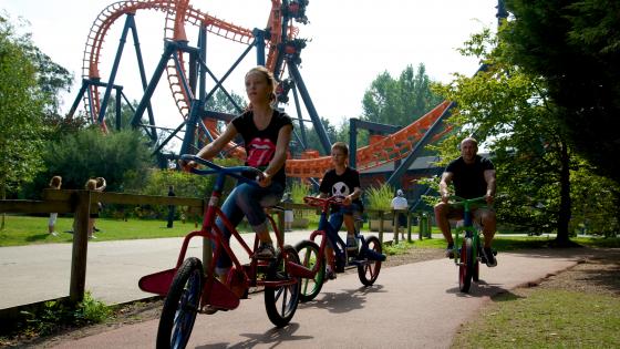 Photo d'un papa et ses enfants sur les Velos Excentriques, l'attraction historique du parc Bagatelle 